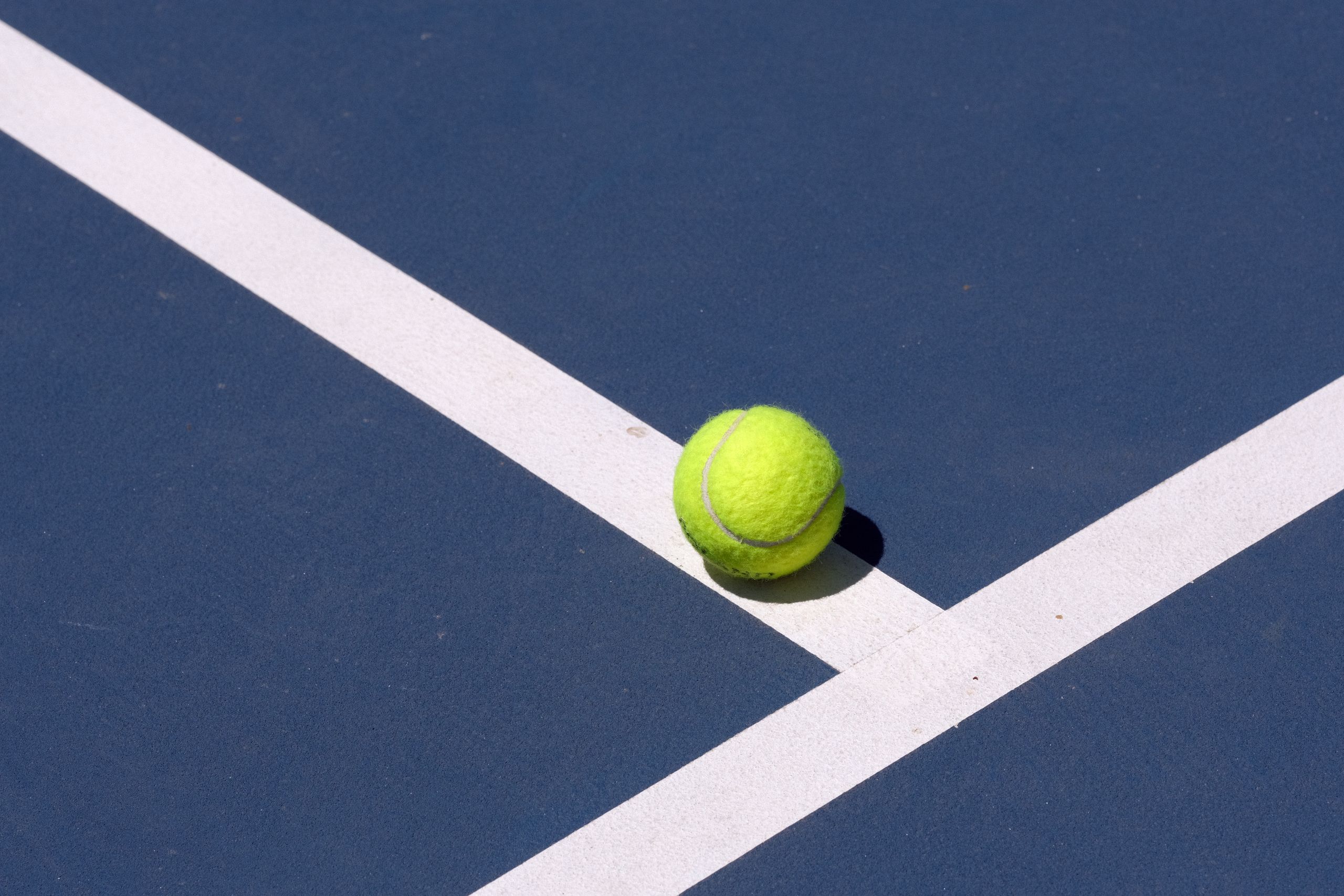 Photo of a tennis ball landing on a court line