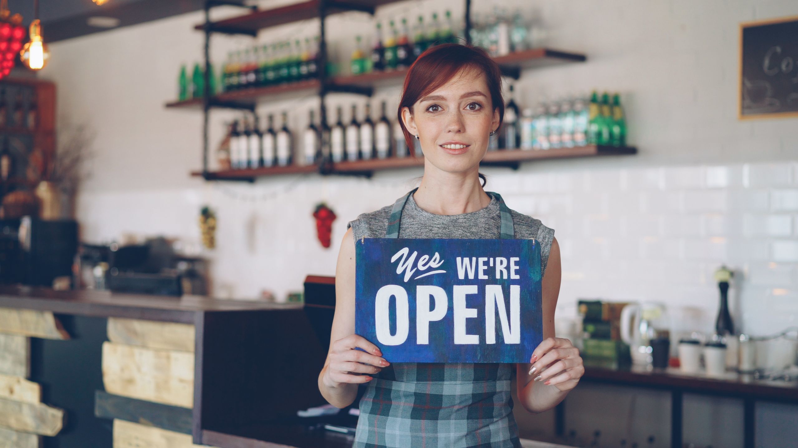 Photo of a café owner holding an open sign